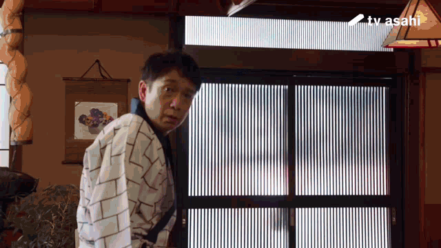 a man is standing in front of a door with a tv asahi logo behind him