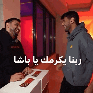 two men are standing next to each other in a hallway and one of them is wearing a grey hoodie .