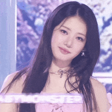 a close up of a girl with long hair wearing a pink dress and a necklace .