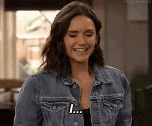 a woman in a denim jacket is smiling and saying i ...