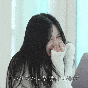 a woman with long black hair covering her mouth with her hands in a foreign language