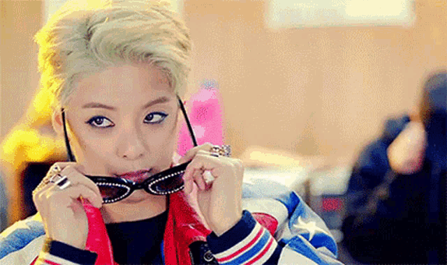 a woman wearing a red , white , and blue jacket is putting on a pair of sunglasses .