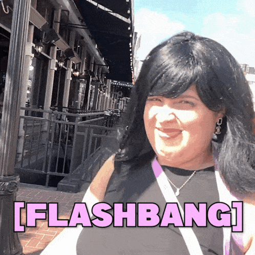 a woman is smiling in front of a sign that says [ flashbang ] on it