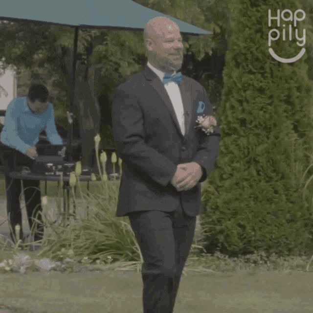 a man in a suit and bow tie is walking down the aisle in front of a sign that says hop pillu