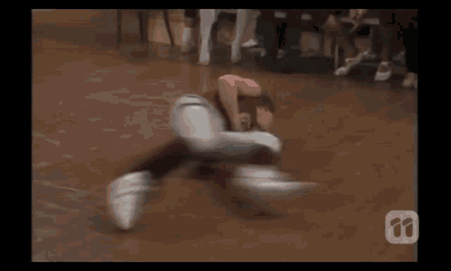 a group of women are sitting in chairs watching a person do a flip on the floor