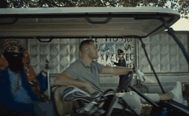 a man driving a golf cart with a sign behind him that says xvabec
