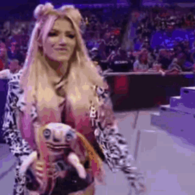 a woman is holding a stuffed animal in her hands in a wrestling ring .