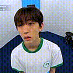 a young man wearing a white shirt with a green collar is sitting on a blue floor .