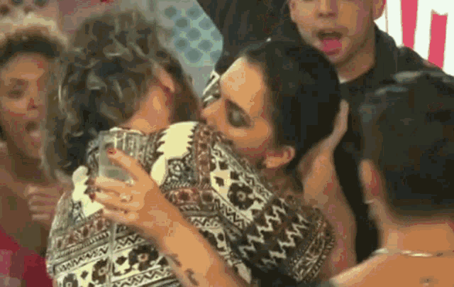 two women are hugging each other in a crowd of people .