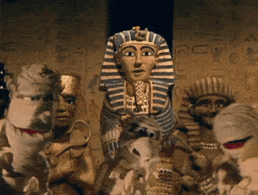 a group of mummy puppets are standing in front of a wall with egyptian writing