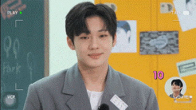 a young man in a suit stands in front of a chalkboard with the word park on it