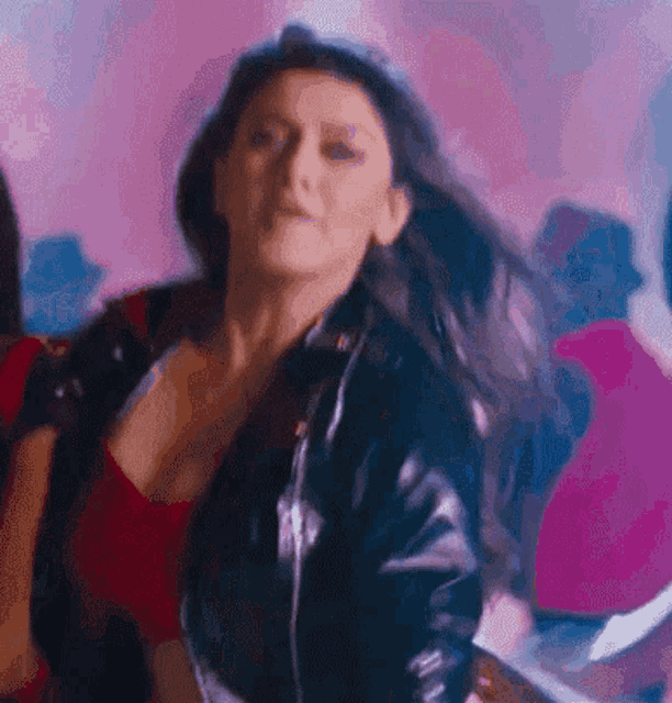 a woman in a black leather jacket is dancing in a club .