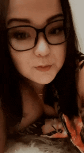a close up of a woman wearing glasses and a flowered shirt .