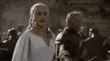 a woman in a white dress is standing next to a man in a armor .
