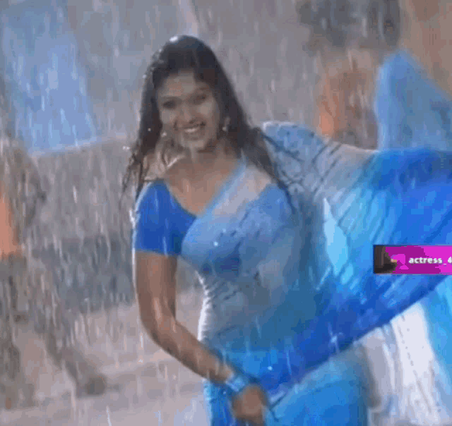 a woman in a blue and white striped saree is smiling