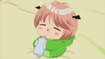 a baby with pink hair and horns is laying on a bed next to a bottle .