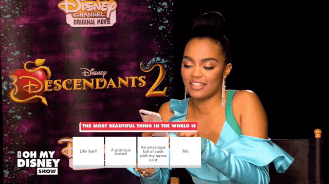 a woman sitting in front of a disney channel original movie poster for descendants 2
