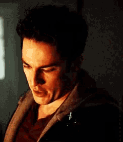 a close up of a man 's face in a dark room with a hoodie on