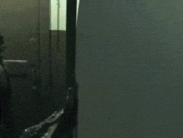 a person in a hoodie is standing in a dark room