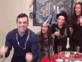 a group of people are sitting at a table with a bottle of champagne and drinks .