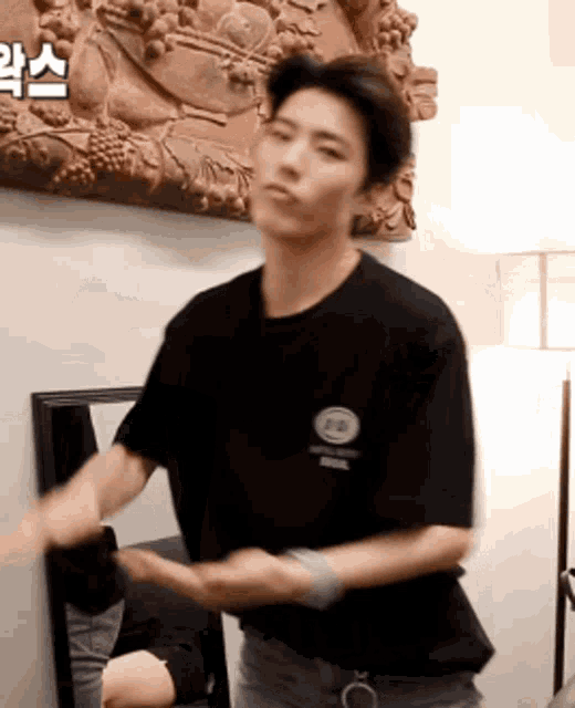 a man in a black t-shirt is dancing in front of a mirror in a room
