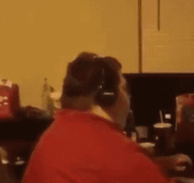 a man in a red shirt is wearing headphones while sitting in front of a computer .