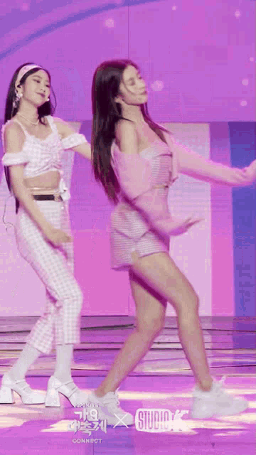 two women are dancing on a stage with studio k written on the bottom of the screen