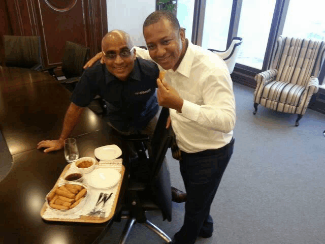 two men are posing for a picture with a tray of food on a table
