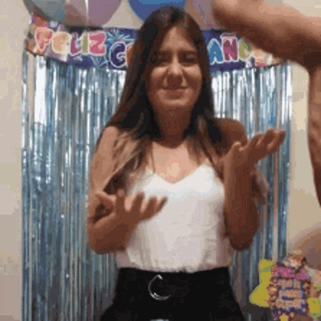 a woman standing in front of a feliz cumpleanos banner
