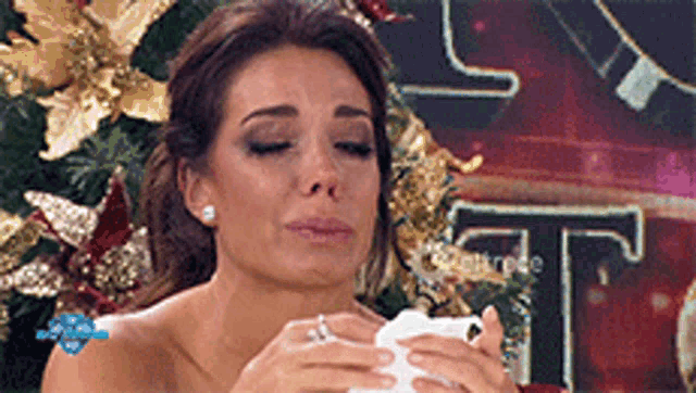 a woman crying in front of a christmas tree