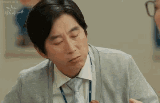 a man in a suit and tie is sitting at a table eating a piece of meat .