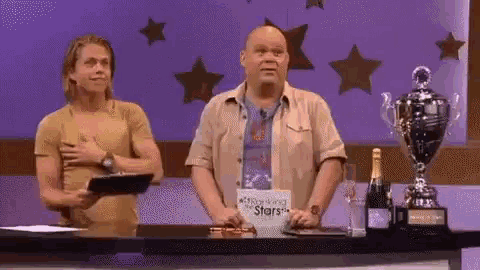 two men are standing in front of a table with a sign that says ' outstanding the stars ' on it
