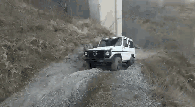 a white suv is driving down a dirt road .