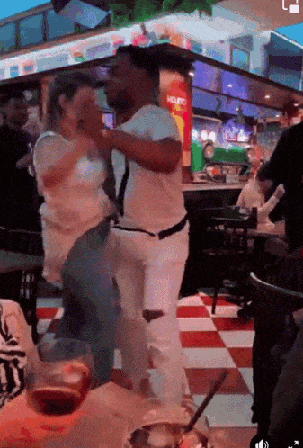a man and a woman are dancing in a restaurant with a mojito sign in the background