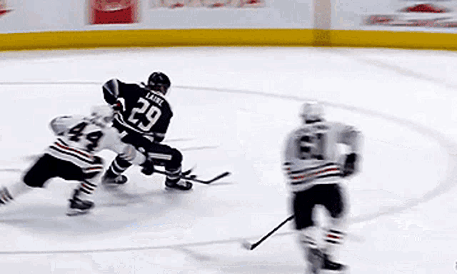 a hockey player with the number 29 on his jersey is being chased by two other players