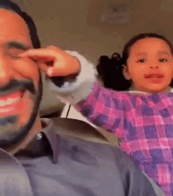 a man with a beard is holding a little girl in his lap