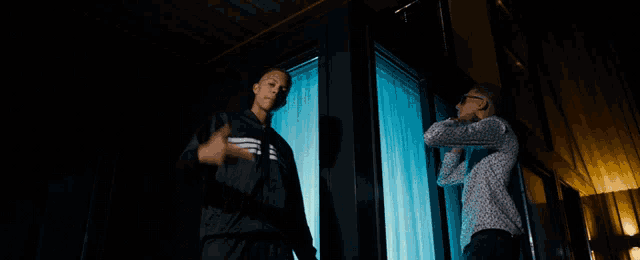 a man in a black adidas jacket is standing next to another man
