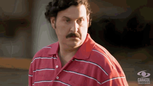 a man with a mustache is wearing a red and white striped shirt with caracol television written on the bottom