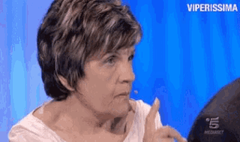 a woman is making a funny face and pointing her finger at the camera .