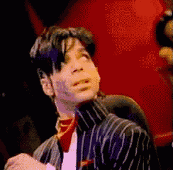 a man wearing a striped jacket and a red scarf is singing into a microphone .