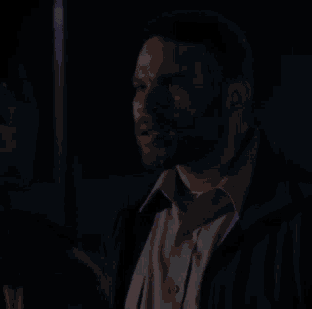 a man with a beard is standing next to another man in a dark room .