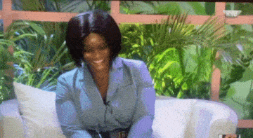 a woman is smiling while sitting on a white couch on a tv screen .