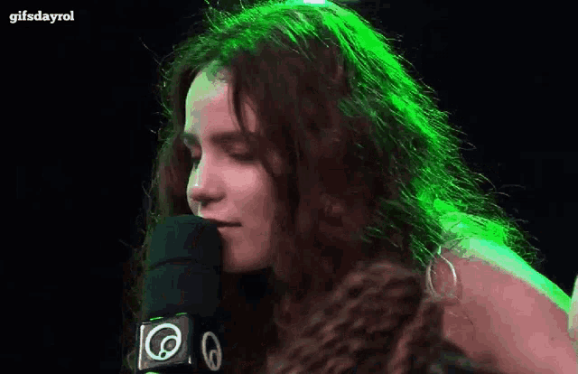 a woman with long hair is standing in front of a microphone with the number 6 on it .