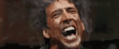 a close up of a man screaming with blood on his face .