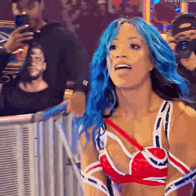 a woman with blue hair and a red , white and blue outfit is standing in front of a fence .