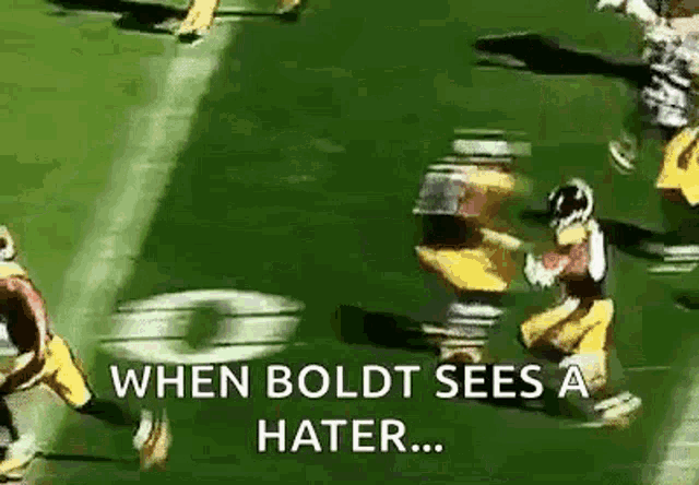 a group of football players are running on a field with the words `` when boldt sees a hater ... '' .