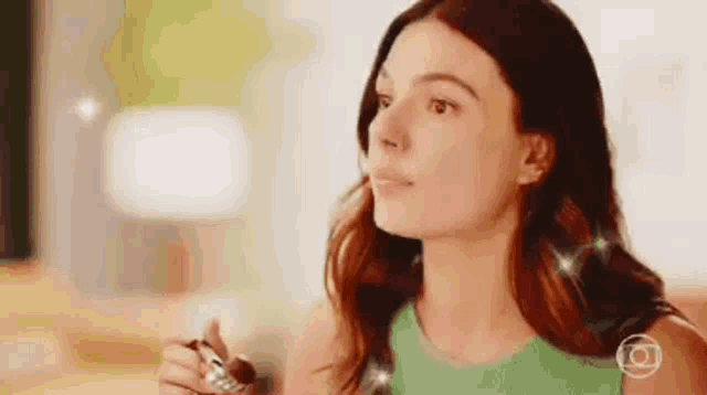 a woman in a green dress is holding a pen in her hand and looking up .