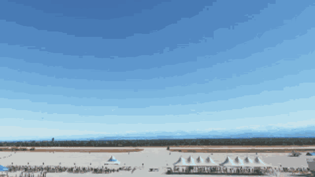a group of tents are lined up on a runway with mountains in the background