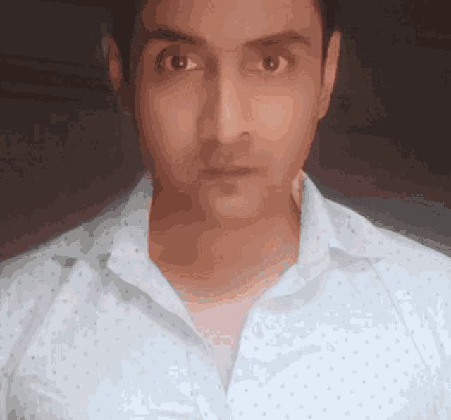 a man wearing a white shirt with polka dots on it looks at the camera