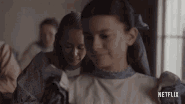 a girl in a white dress with a blue bow in her hair is standing next to another girl .